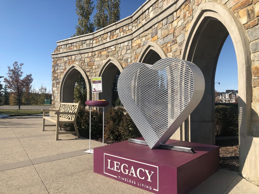 A photo of the Legacy Hearts sculpture in front of an archway and bench.