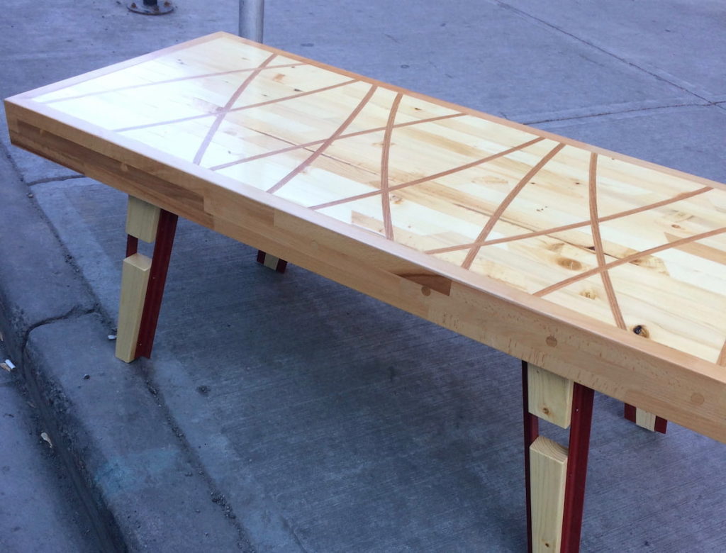 An intricate table with curved wood inlays sits on a curb.