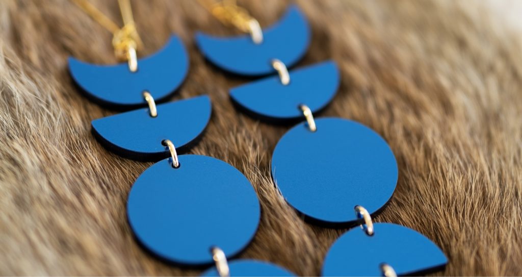 Blue laser cut earrings several laser cut symbols hanging in a chain.