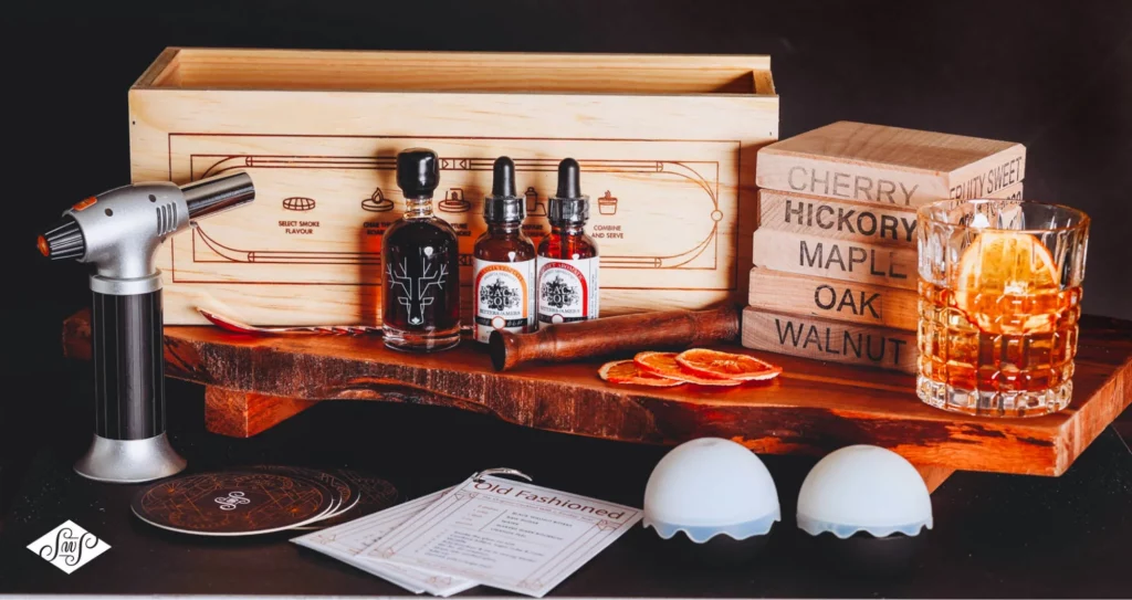 a product photo of wooden engraved boxes and casters with dropper bottles and a mixed drink