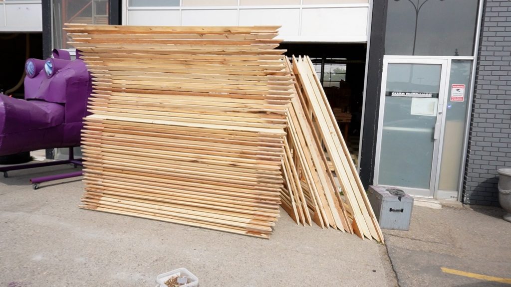 A stack of over 40 large wood triangles in a parking lot.