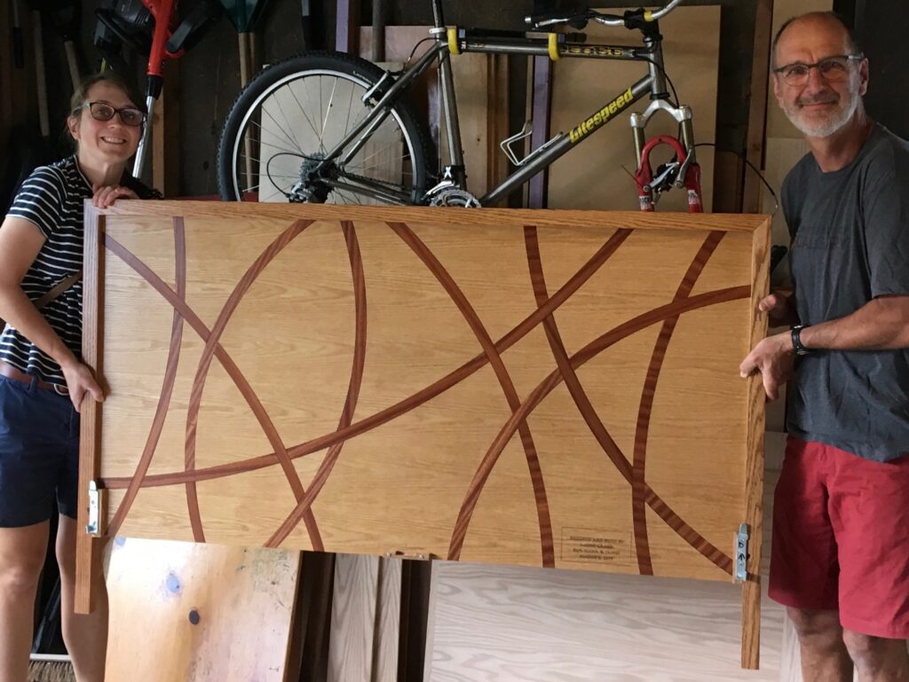 Two people hold up a intricate wood table.