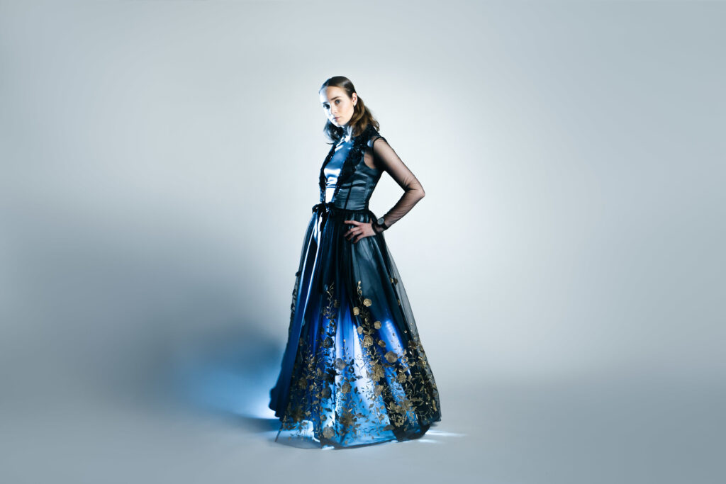 A model looks at the camera while wearing a blue gown.